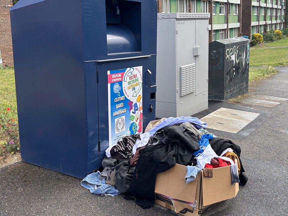 Donations of clothes piled up outside reycling bins