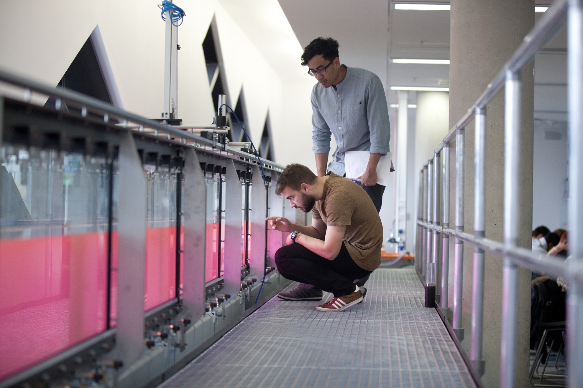 Engineering students examine an experiment in a fluid tank