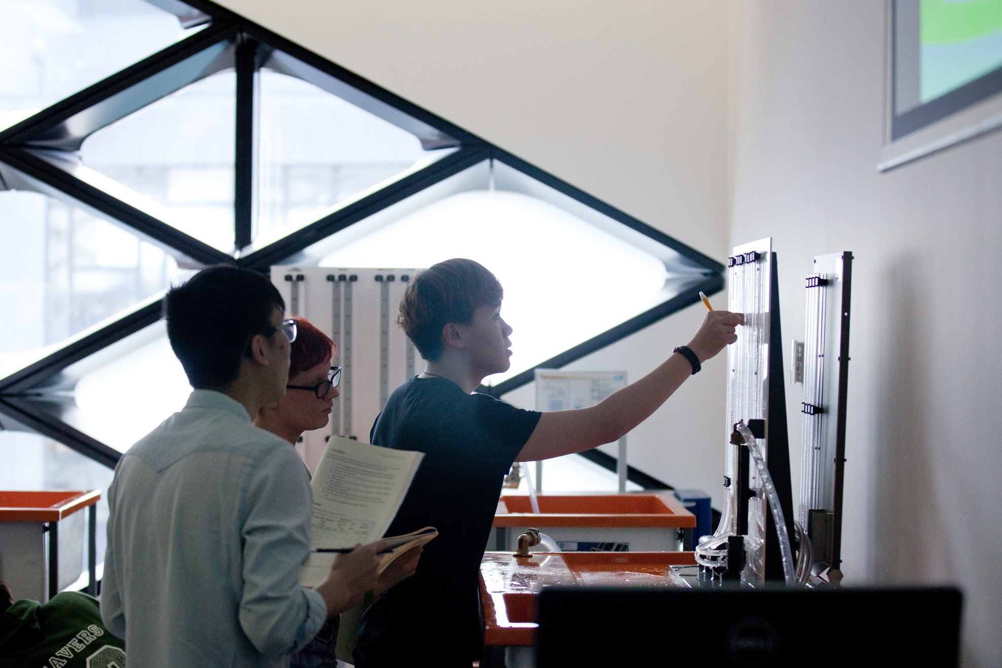 Students are performing an experiment in the Fluids Engineering lab and taking readings from the insrumentation