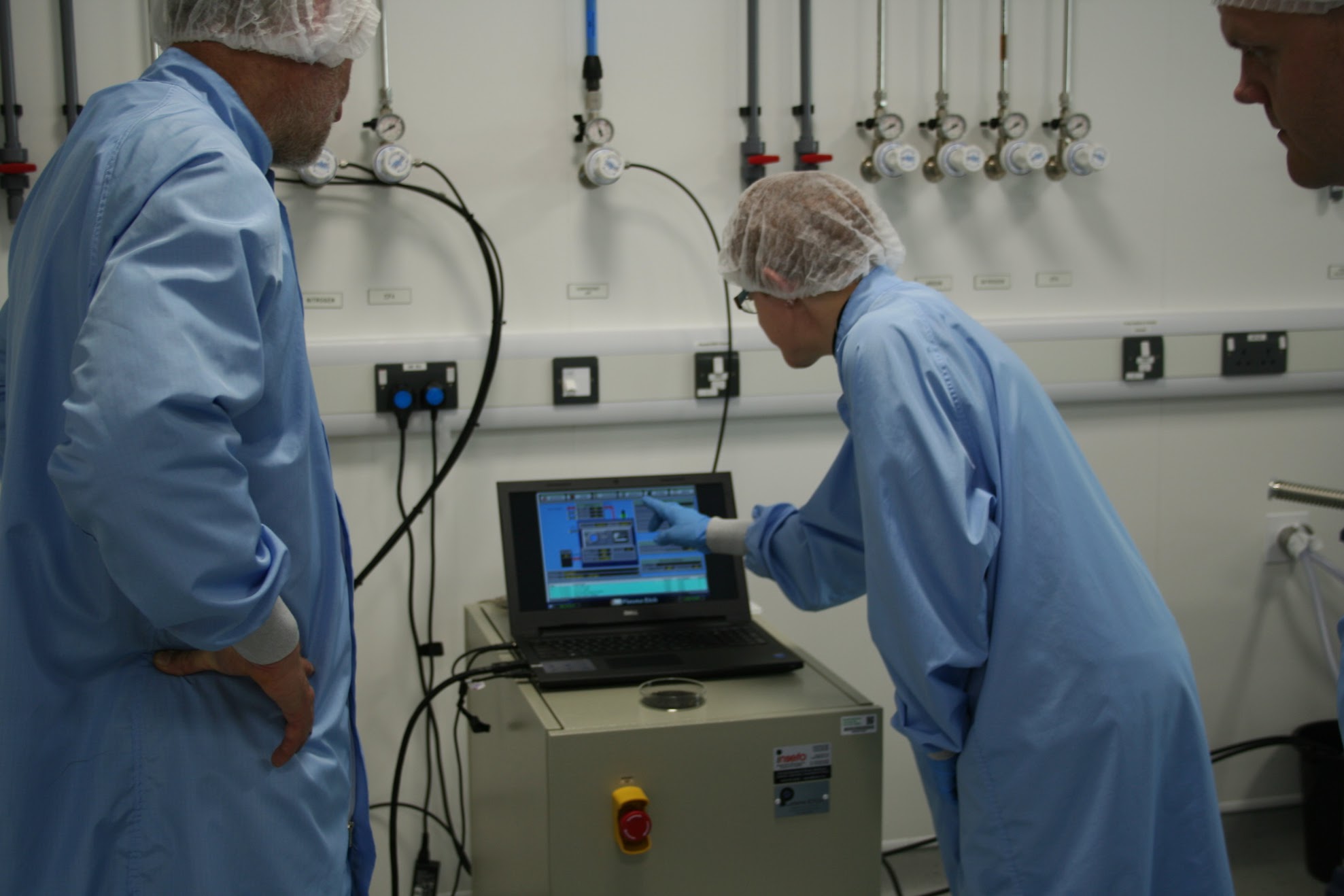 Technicians in protective clothing check computer read outs next to a pressure valve