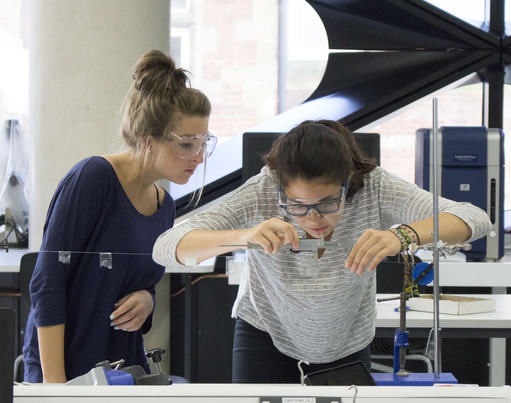 Students measure a sample in a vice