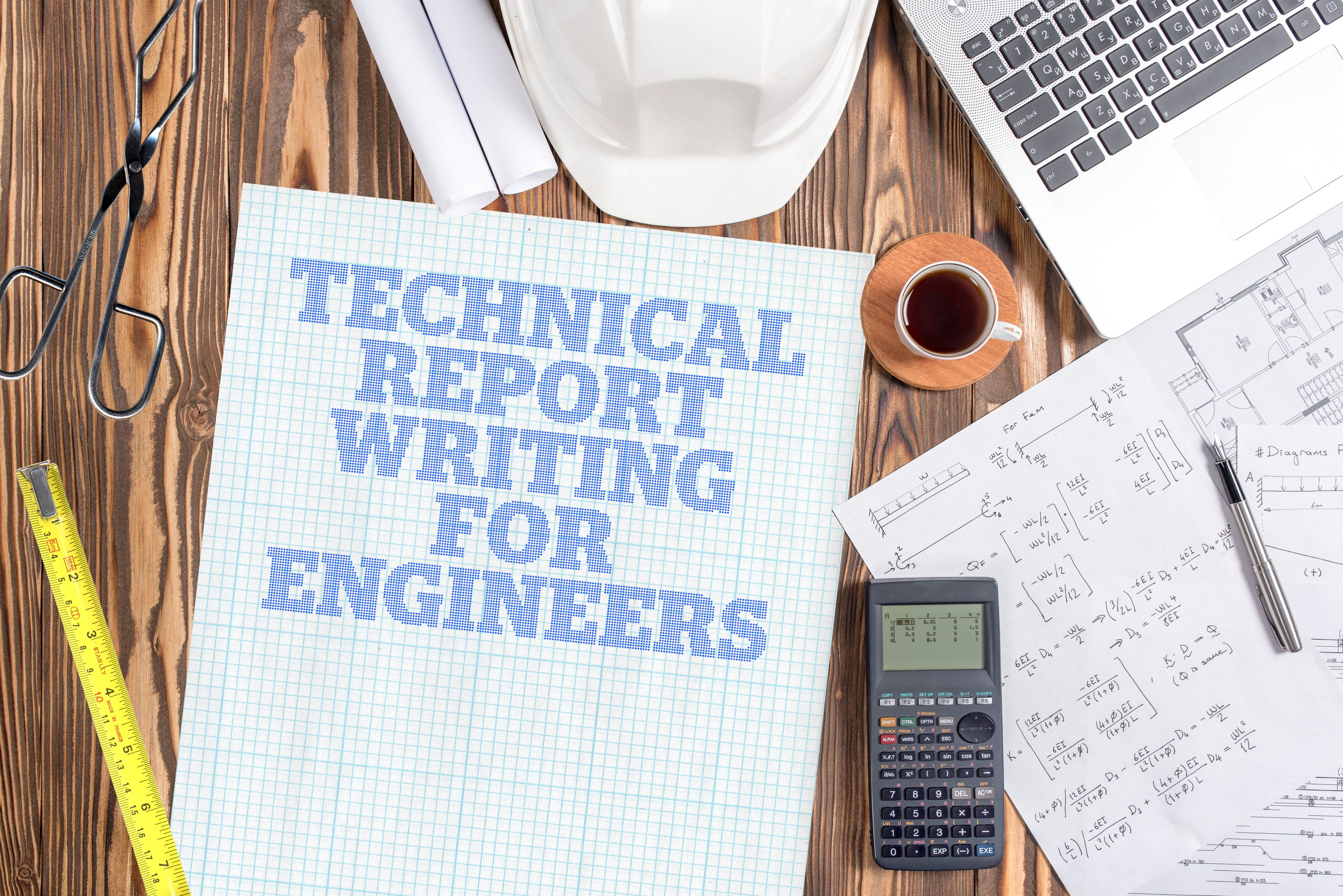 'Technical Report Writing For Engineers' printed on graph paper, on an engineer's desk